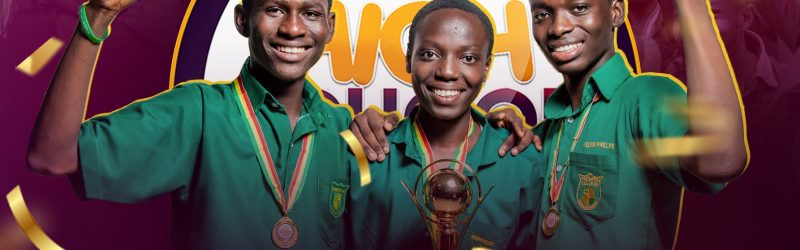 Three Prempeh College debaters with medals hold a trophy aloft, smiling.